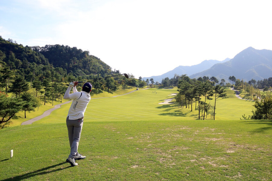 golf player on golf course hitting with driver
